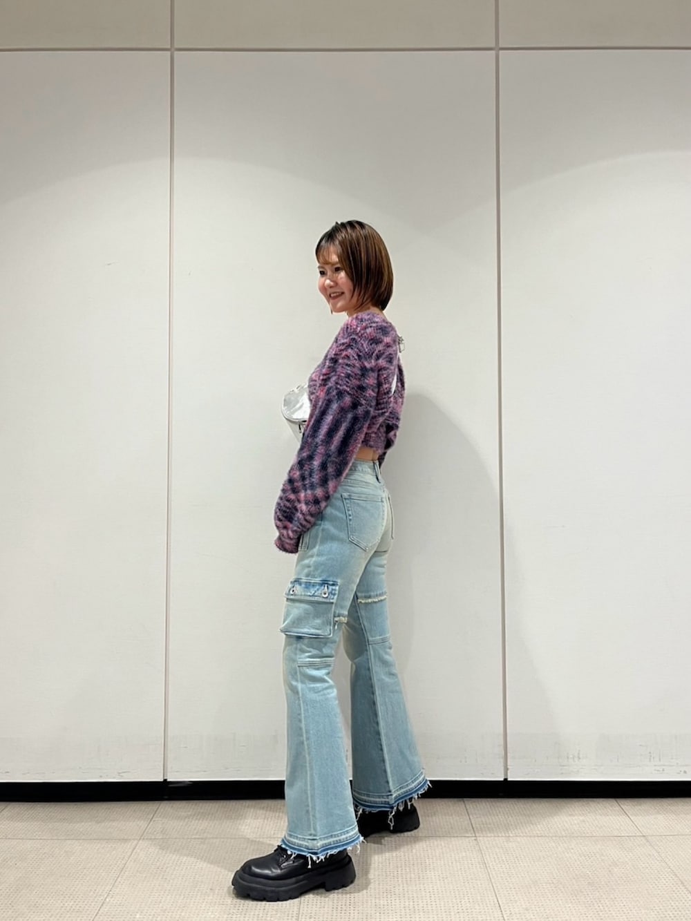 ピンク系のニット/セーター、シルバー系のボディバッグ/ウエストポーチ、ブルー系のデニムパンツを着用したレディースの冬コーディネートの2枚目の写真