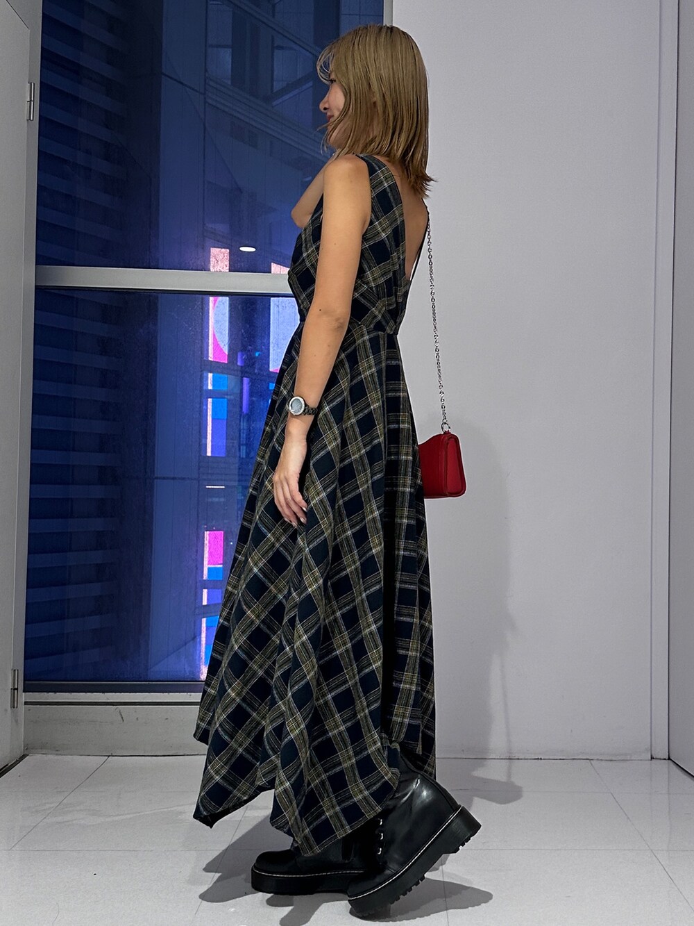 ブルー系のワンピース、レッド系のショルダーバッグ、ブラック系のブーツを着用したレディースの秋コーディネートの2枚目の写真