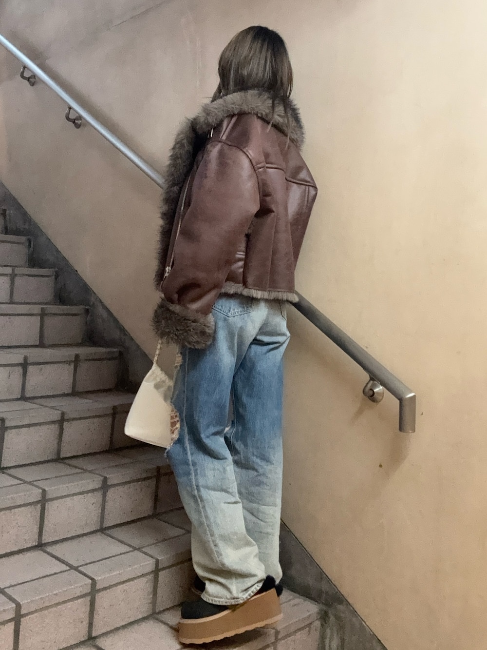 ブラウン系のブルゾン、ブラック系のTシャツ/カットソー、ブルー系のデニムパンツを着用したレディースの秋コーディネートの3枚目の写真