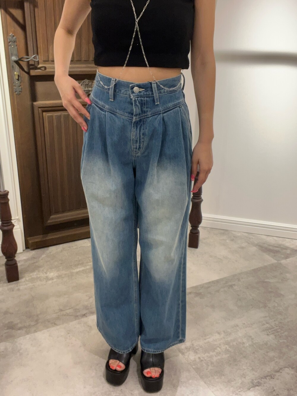 ブラック系のタンクトップ、ブルー系のデニムパンツ、グリーン系のショルダーバッグを着用したレディースの夏コーディネートの4枚目の写真