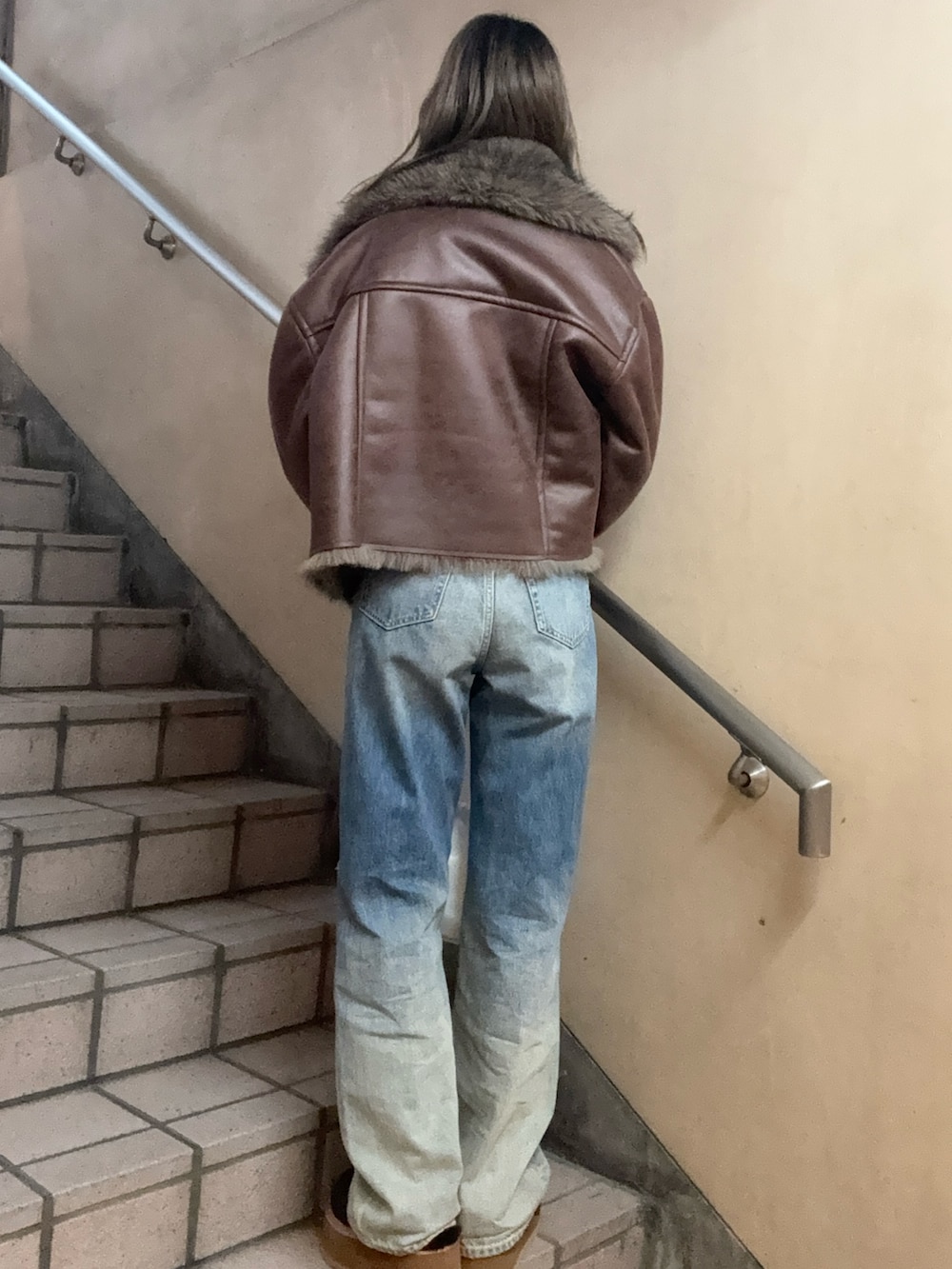 ブラウン系のブルゾン、ブラック系のTシャツ/カットソー、ブルー系のデニムパンツを着用したレディースの秋コーディネートの4枚目の写真