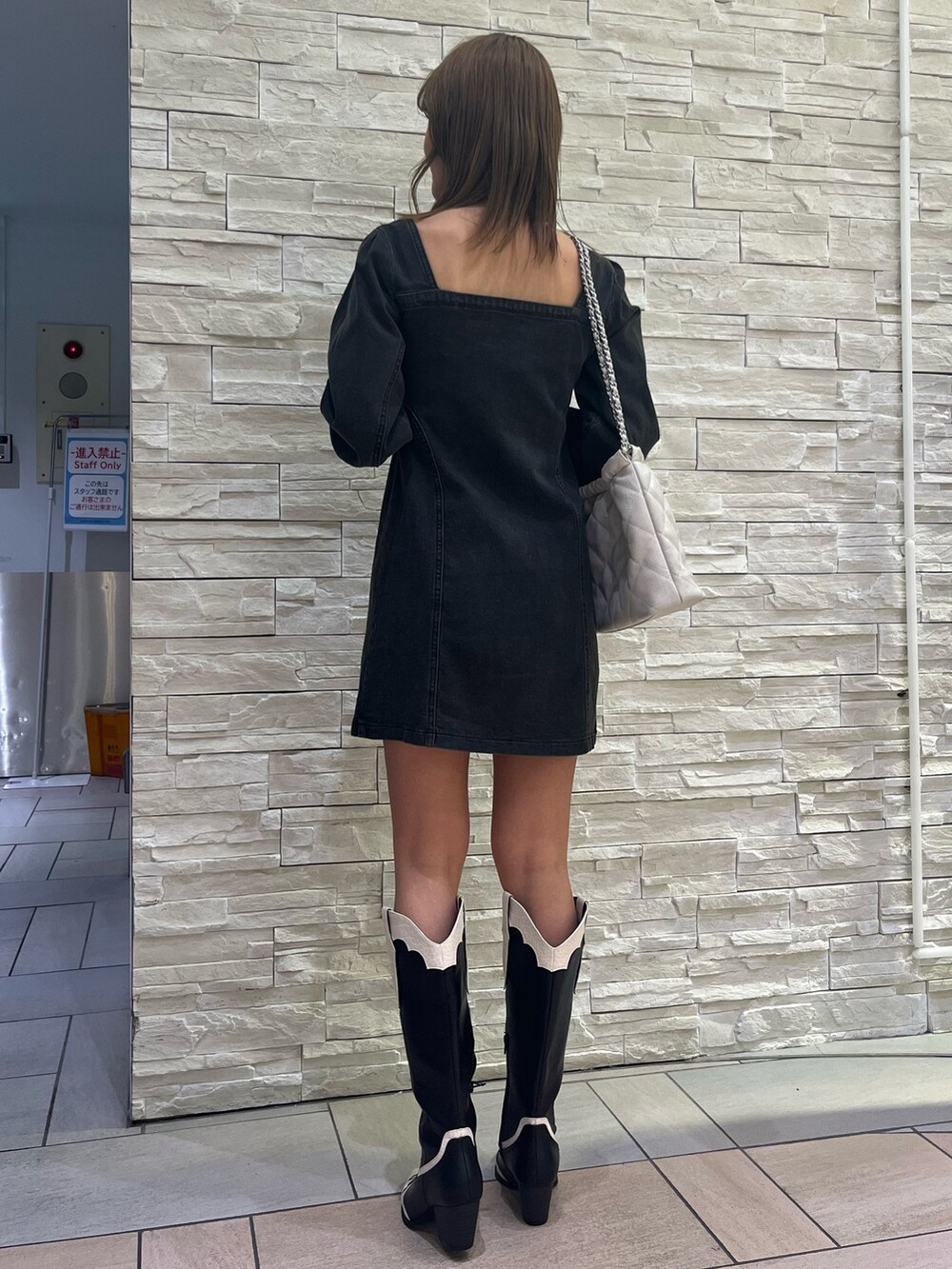 ブラック系のワンピース、ホワイト系のショルダーバッグ、その他のブーツを着用したレディースの冬コーディネートの3枚目の写真