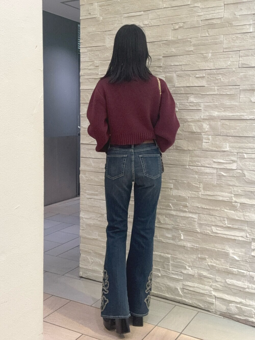 レッド系のニット/セーター、ブルー系のデニムパンツ、その他のブーツを着用したレディースの秋コーディネートの3枚目の写真