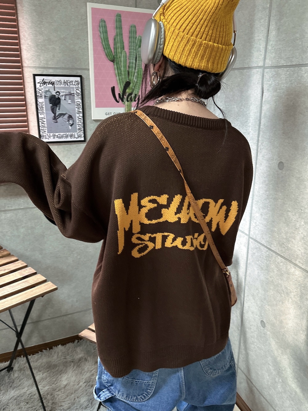 イエロー系のブーツ、ブラウン系のニット/セーター、ブルー系のデニムパンツを着用したレディースの秋コーディネートの3枚目の写真