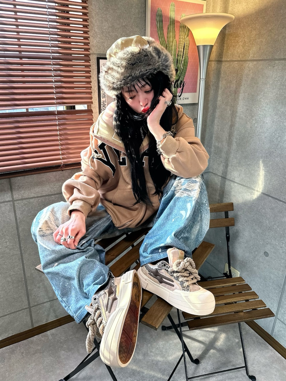 ブラウン系のパーカー、ブルー系のデニムパンツ、ブラウン系のスニーカーを着用したレディースの冬コーディネートの2枚目の写真