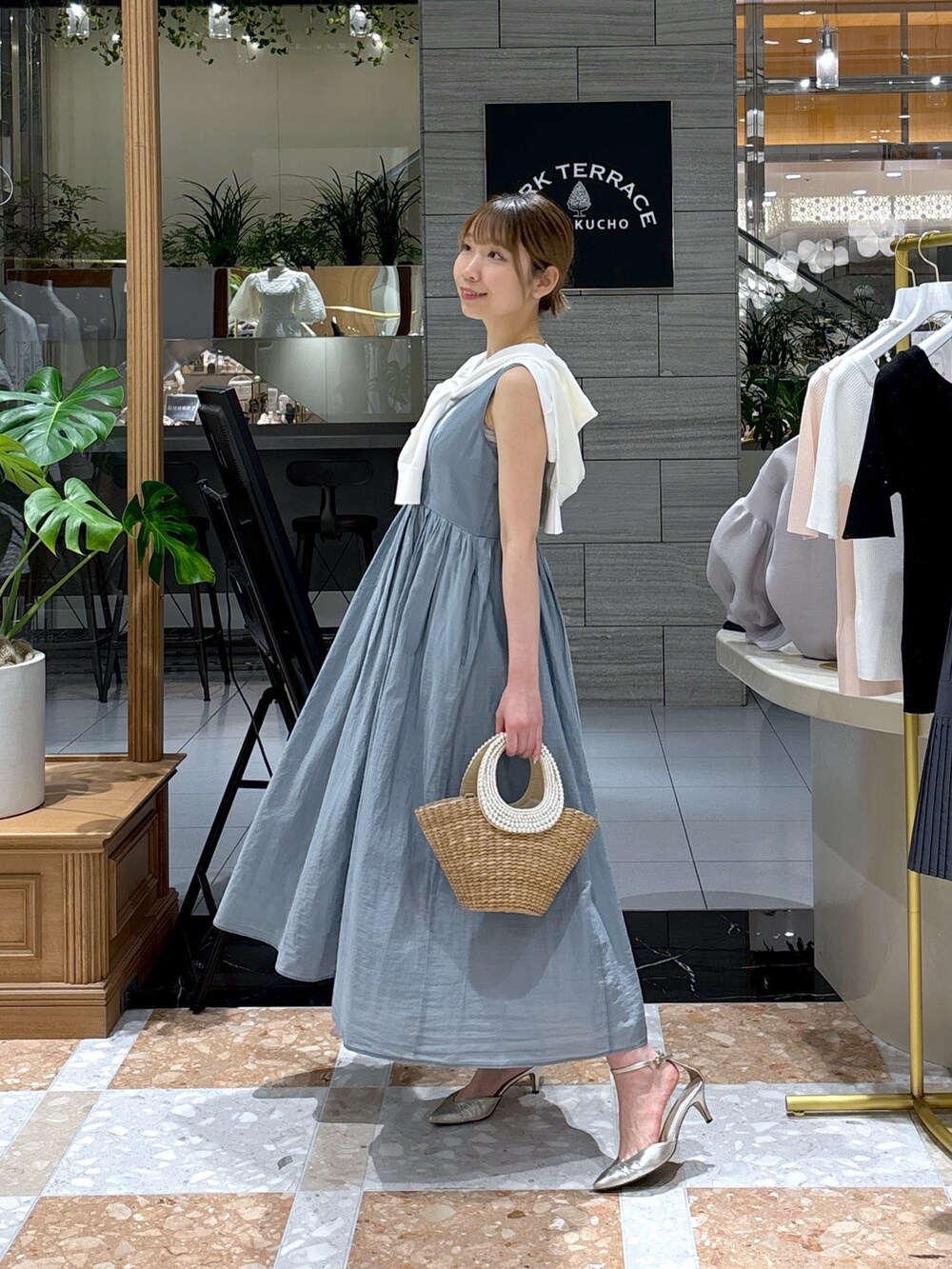 ブルー系のワンピース、ホワイト系のカーディガン/ボレロ、ベージュ系のかごバッグを着用したレディースの春コーディネートの2枚目の写真