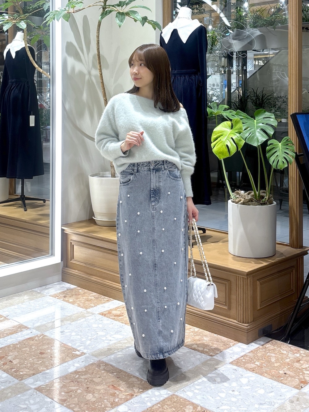 グリーン系のニット/セーター、ブルー系のデニムスカートを着用したレディースの冬コーディネートの2枚目の写真