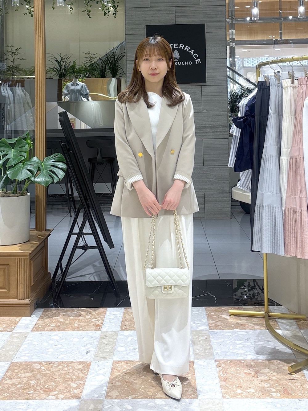 ホワイト系のニット/セーター、ベージュ系のテーラードジャケット、ホワイト系のスラックスを着用したレディースの春コーディネートの2枚目の写真