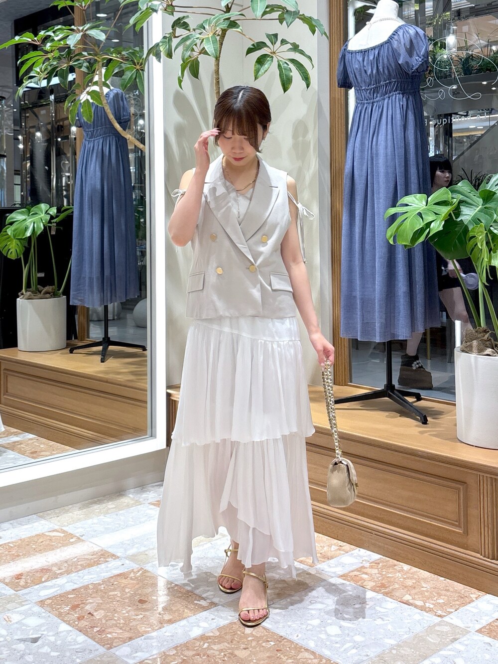 ベージュ系のベスト、ホワイト系のスカートを着用したレディースの秋コーディネートの2枚目の写真