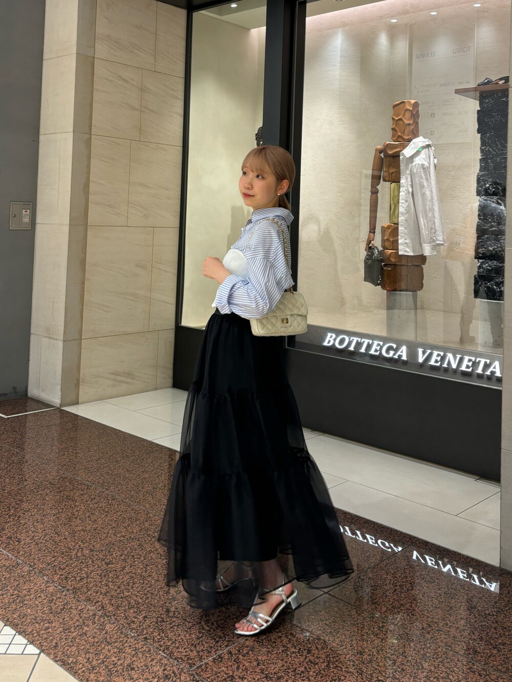 ブラック系のスカート、ホワイト系のニット/セーター、ホワイト系のショルダーバッグを着用したレディースの夏コーディネートの3枚目の写真