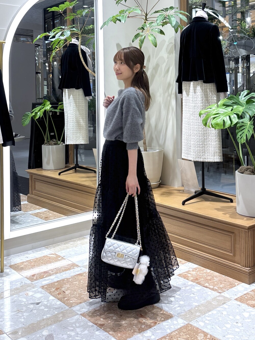 グレー系のニット/セーター、ブラック系のスカートを着用したレディースの秋コーディネートの2枚目の写真