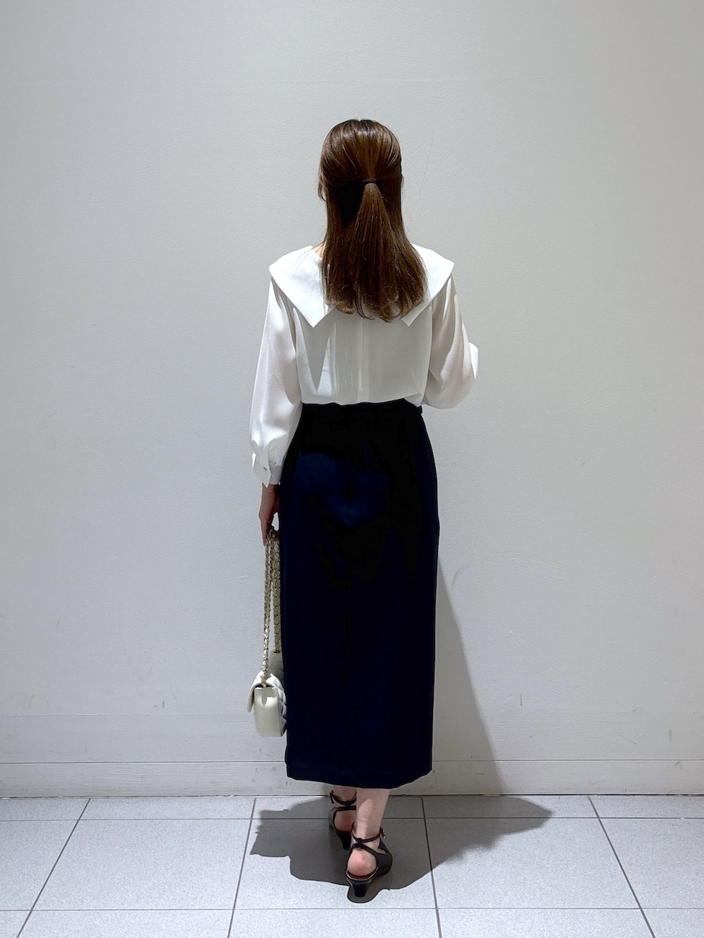 ブルー系のスカート、ホワイト系のシャツ/ブラウス、ブラック系のサンダルを着用したレディースの春コーディネートの4枚目の写真