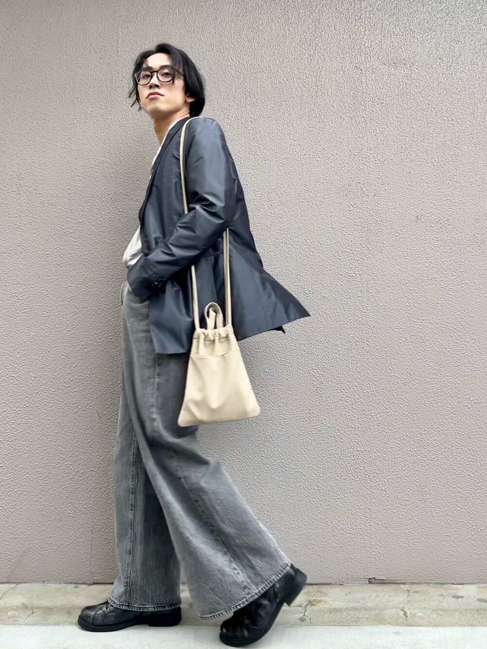 グレー系のデニムパンツ、ベージュ系のショルダーバッグを着用したメンズの春コーディネートの2枚目の写真