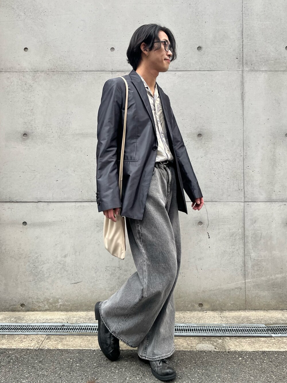 グレー系のデニムパンツ、ベージュ系のショルダーバッグを着用したメンズの春コーディネートの4枚目の写真