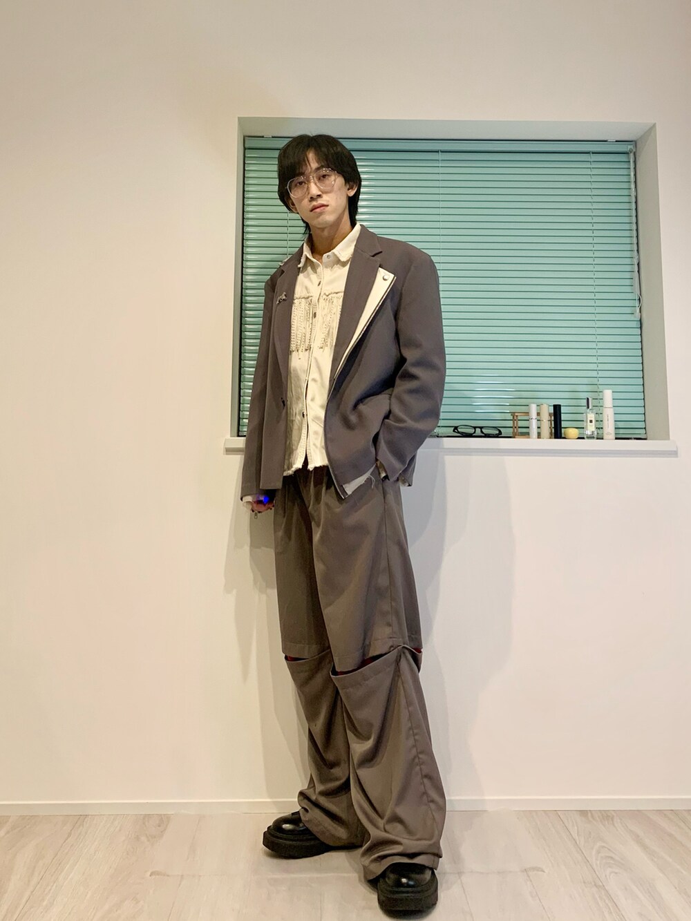 グレー系のテーラードジャケット、グレー系のスラックス、ブラック系のブーツを着用したメンズの春コーディネートの2枚目の写真