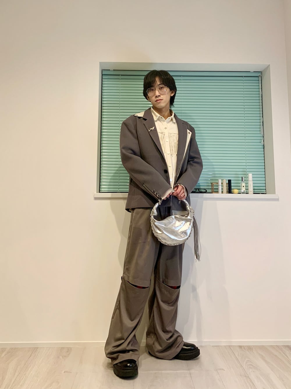 グレー系のテーラードジャケット、グレー系のスラックス、ブラック系のブーツを着用したメンズの春コーディネートの3枚目の写真