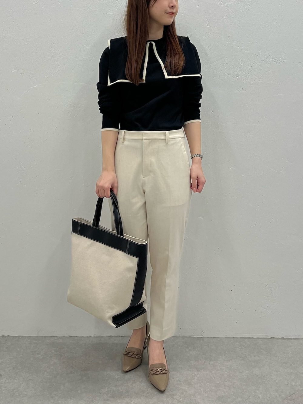 ブラック系のニット/セーター、ブラック系のトートバッグ、ベージュ系のパンツを着用したレディースの春コーディネートの2枚目の写真