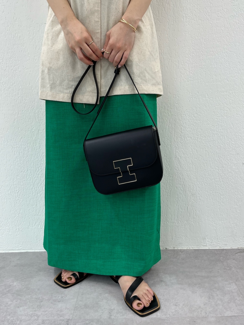 ベージュ系のベスト、グリーン系のワンピース、ブラック系のサンダルを着用したレディースの夏コーディネートの2枚目の写真