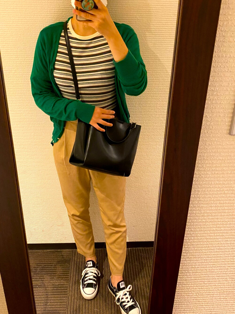 ブラック系のスニーカー、ベージュ系のチノパンツ、ブラック系のショルダーバッグを着用したレディースの秋コーディネートの2枚目の写真