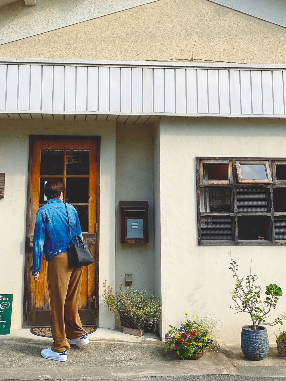 ホワイト系のスニーカー、ブルー系のデニムジャケット、ブラウン系のその他パンツを着用したレディースの夏コーディネートの2枚目の写真