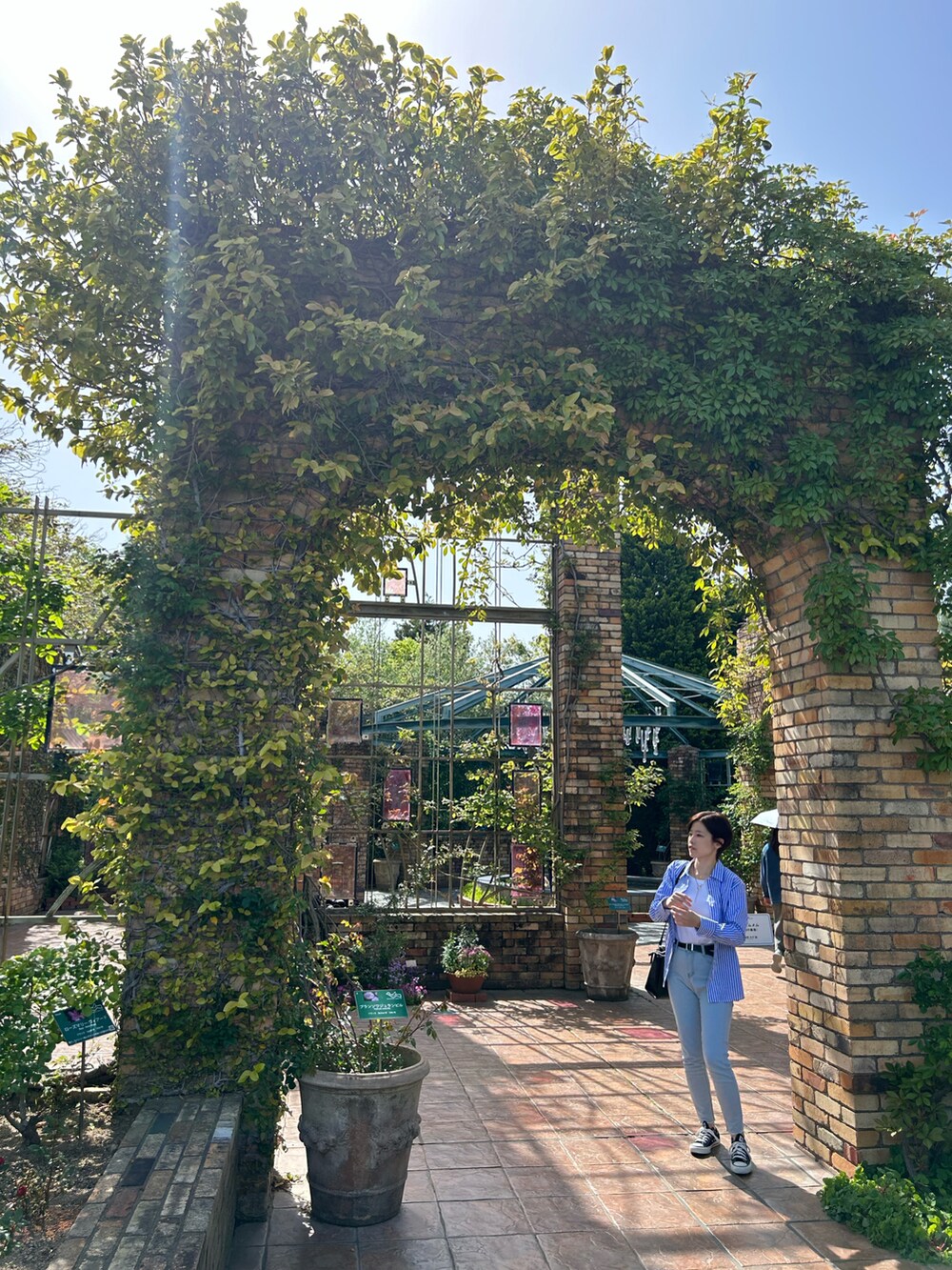 ブルー系のシャツ/ブラウス、ブラック系のスニーカー、ブラック系のショルダーバッグを着用したレディースの春コーディネートの2枚目の写真