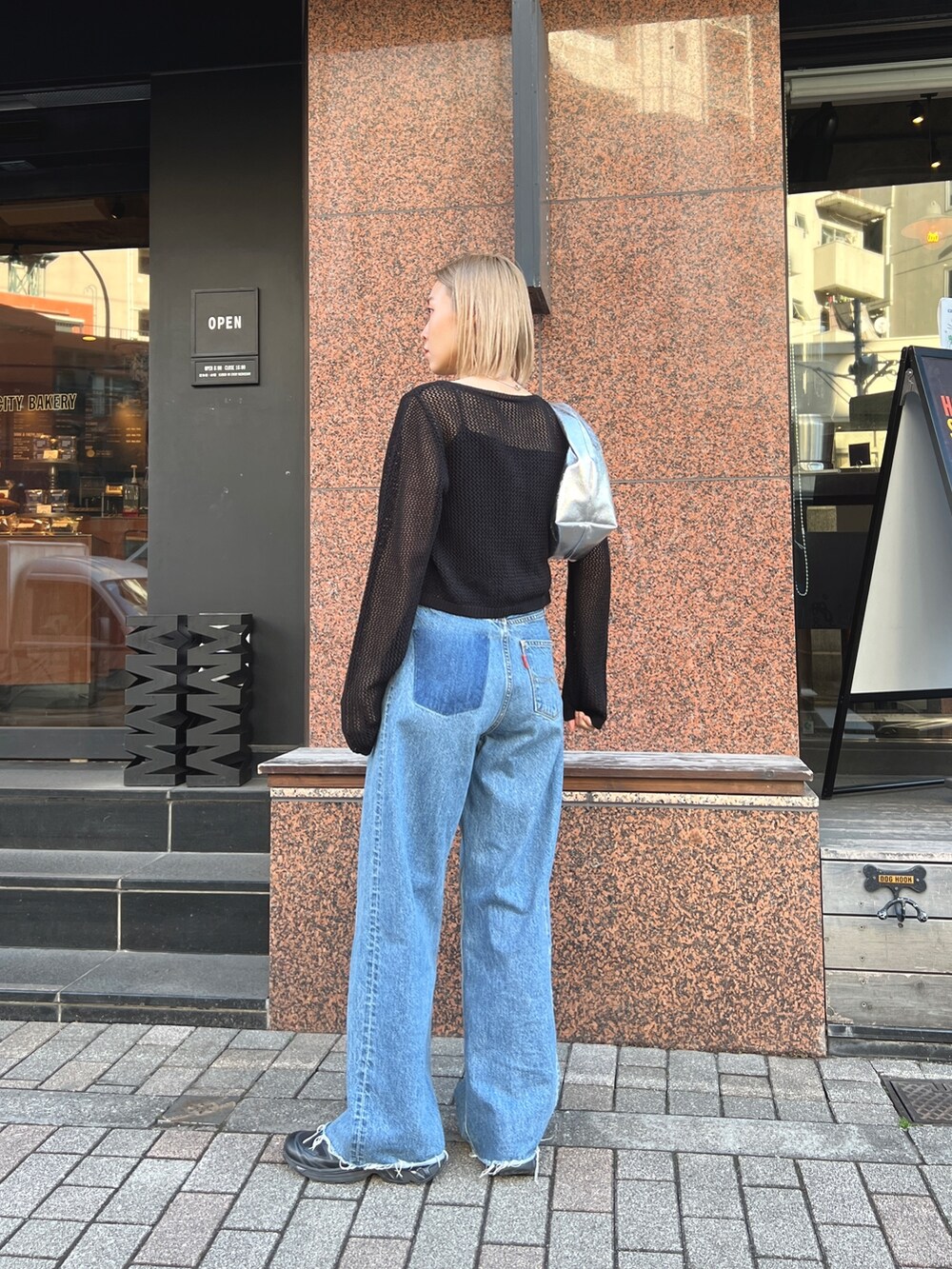 ブルー系のデニムパンツ、ブラック系のスニーカー、ブラック系のカーディガン/ボレロを着用したレディースの春コーディネートの3枚目の写真