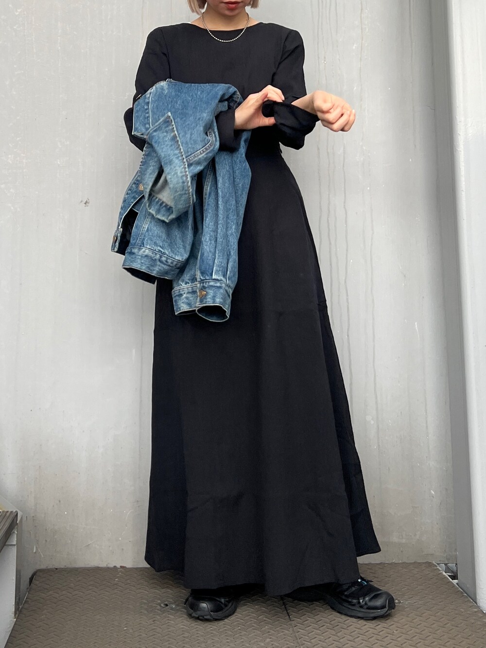 ブラック系のワンピース、ブルー系のデニムジャケット、ブラック系のスニーカーを着用したレディースの冬コーディネートの2枚目の写真