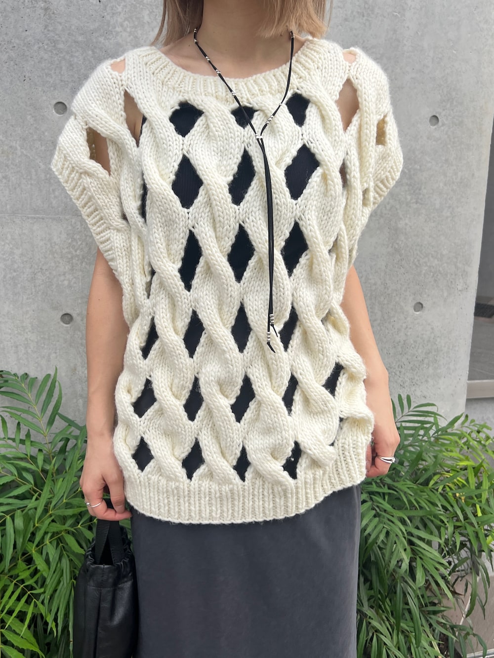 ホワイト系のニット/セーター、グレー系のスカート、ブラック系のショルダーバッグを着用したレディースの春コーディネートの2枚目の写真