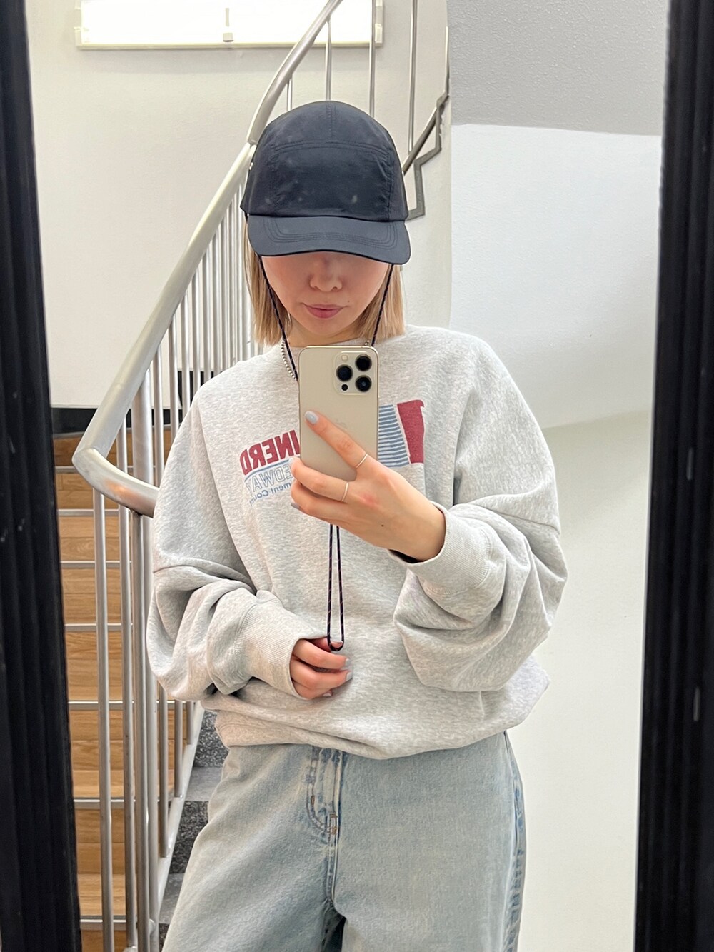 グレー系のスウェット、ブルー系のデニムパンツを着用したレディースの冬コーディネートの2枚目の写真