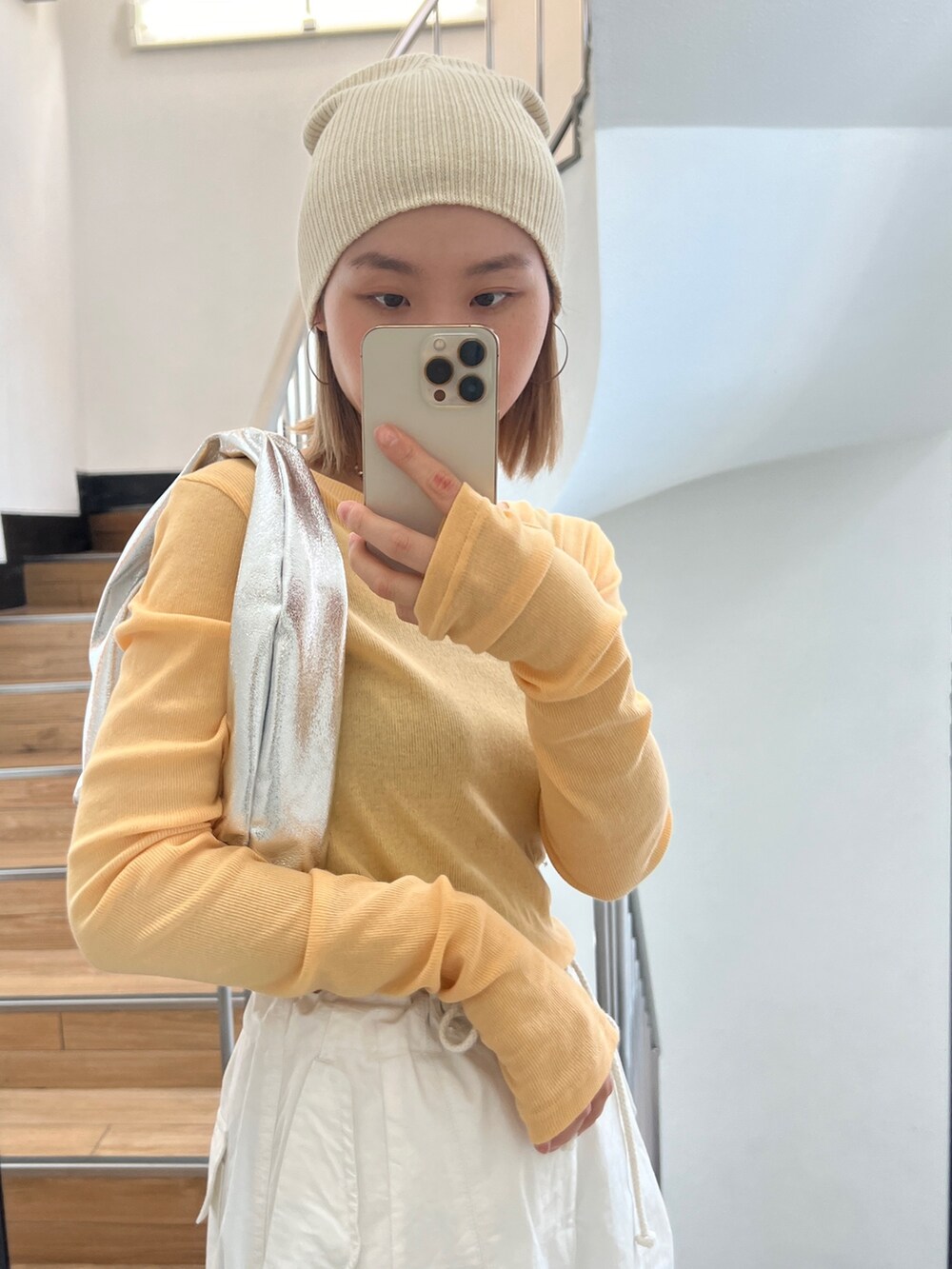 オレンジ系のTシャツ/カットソー、シルバー系のハンドバッグ、ホワイト系のその他パンツを着用したレディースの冬コーディネートの2枚目の写真