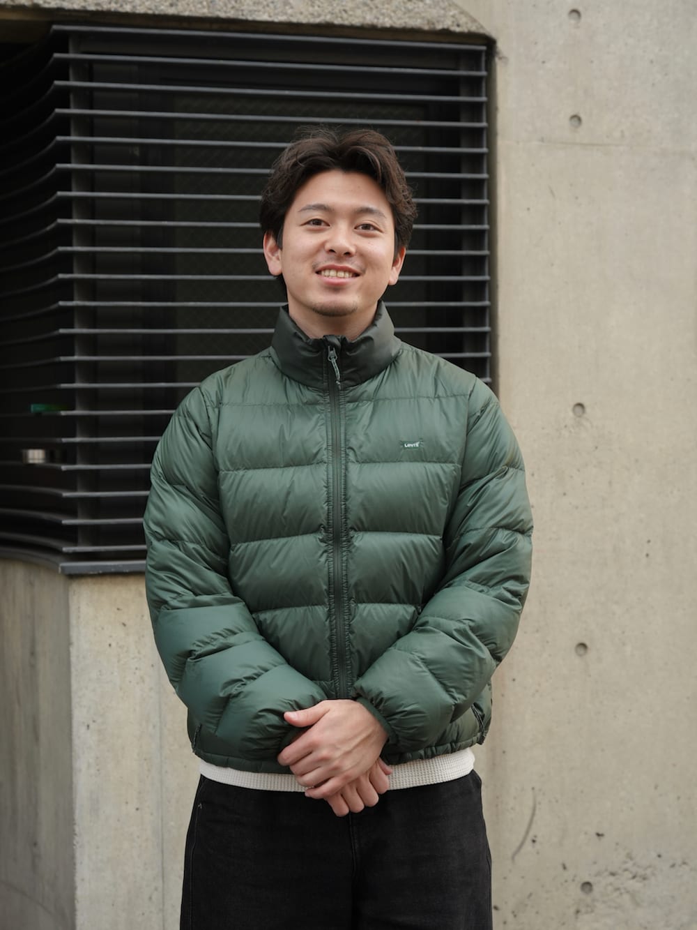 ブラック系のデニムパンツ、ブラック系のドレスシューズ、グリーン系のダウンジャケット/コートを着用したメンズの春コーディネートの3枚目の写真
