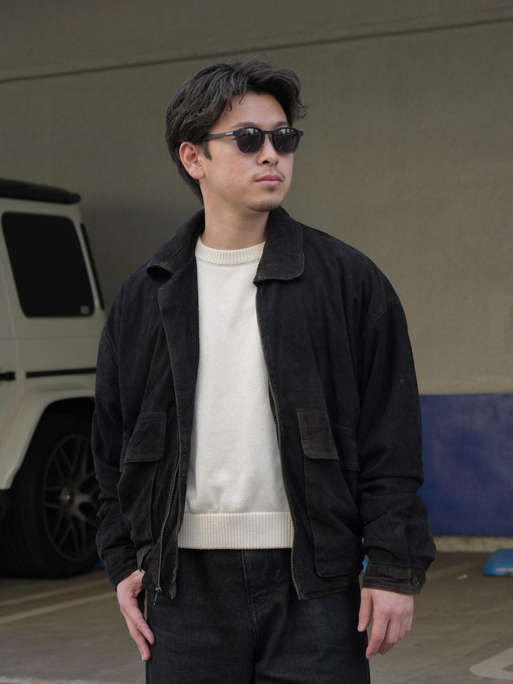 ブラック系のデニムパンツ、ホワイト系のニット/セーター、ブラック系のジャケット/アウターを着用したメンズの春コーディネートの3枚目の写真