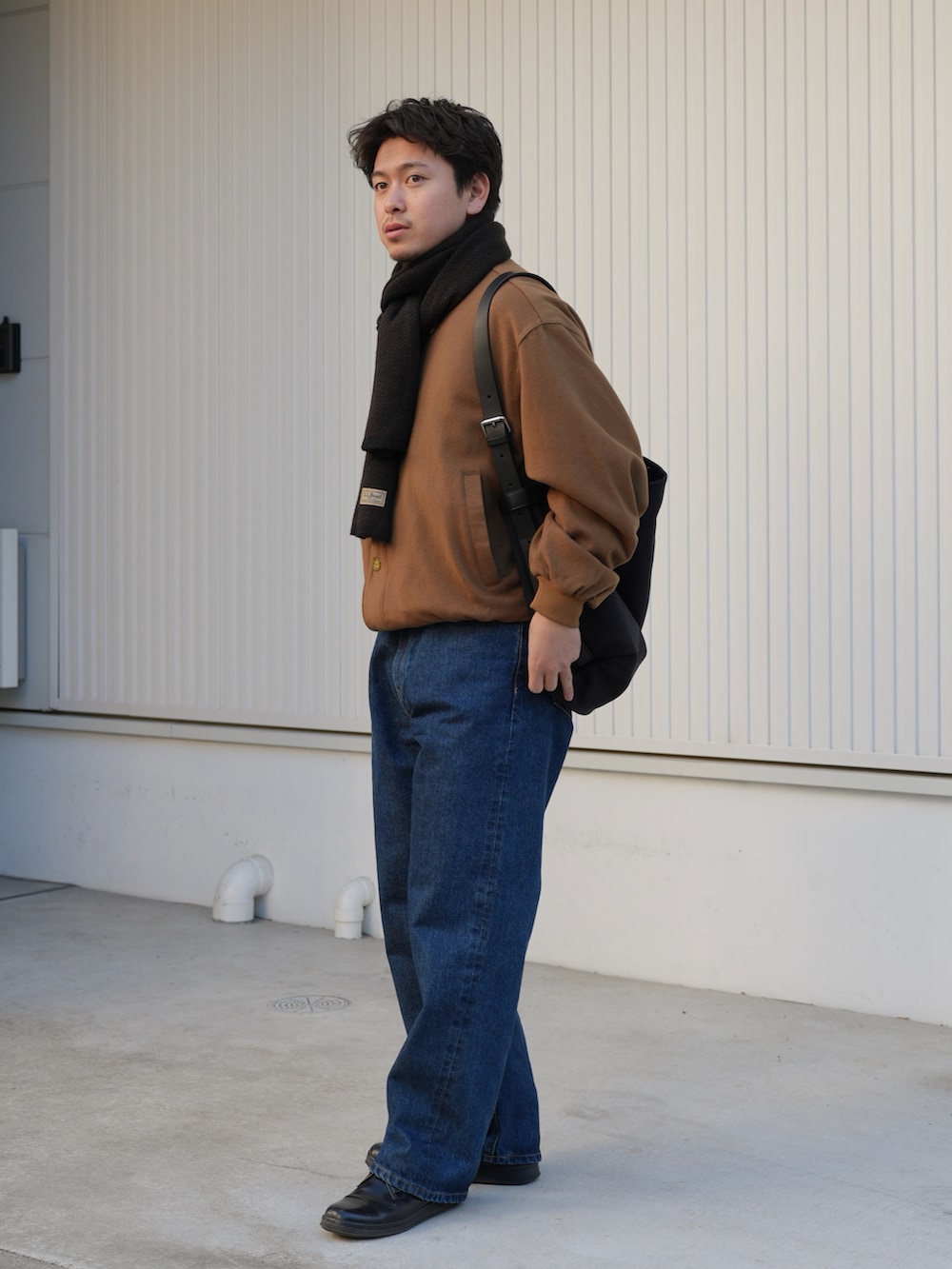 ブルー系のデニムパンツ、ベージュ系のジャケット/アウター、ブルー系のメッセンジャーバッグを着用したメンズの春コーディネートの2枚目の写真