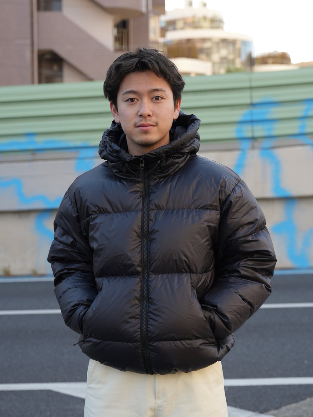 ブラウン系のスニーカー、ブラック系のダウンジャケット/コート、ホワイト系のチノパンツを着用したメンズの冬コーディネートの3枚目の写真