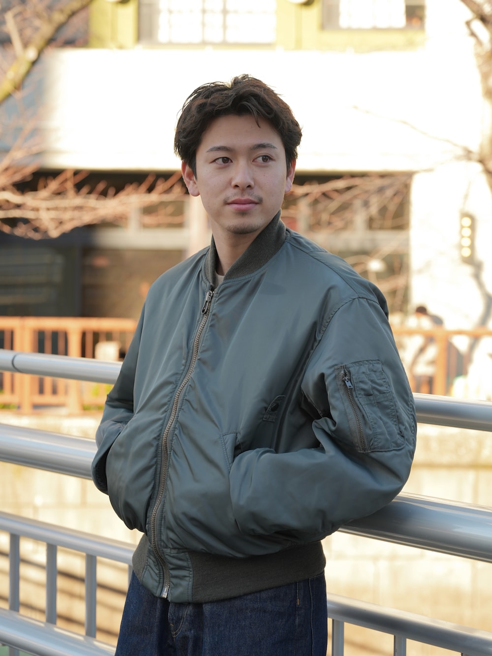 グリーン系のMA-1、ブルー系のデニムパンツ、ブラック系のドレスシューズを着用したメンズの春コーディネートの3枚目の写真