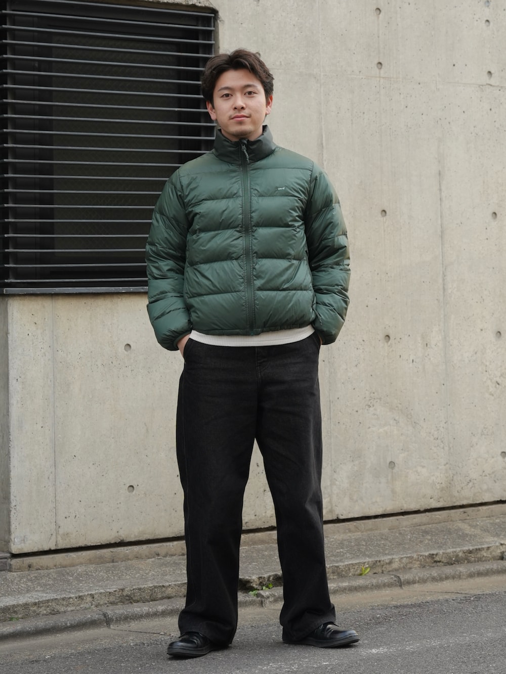 ブラック系のデニムパンツ、ブラック系のドレスシューズ、グリーン系のダウンジャケット/コートを着用したメンズの春コーディネートの2枚目の写真
