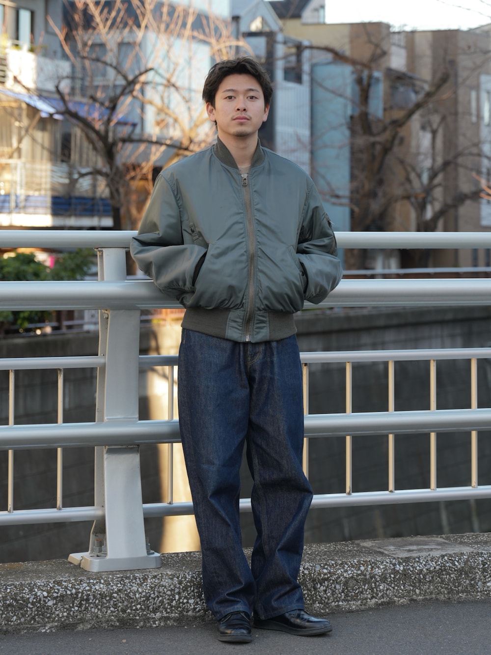 グリーン系のMA-1、ブルー系のデニムパンツ、ブラック系のドレスシューズを着用したメンズの春コーディネートの2枚目の写真