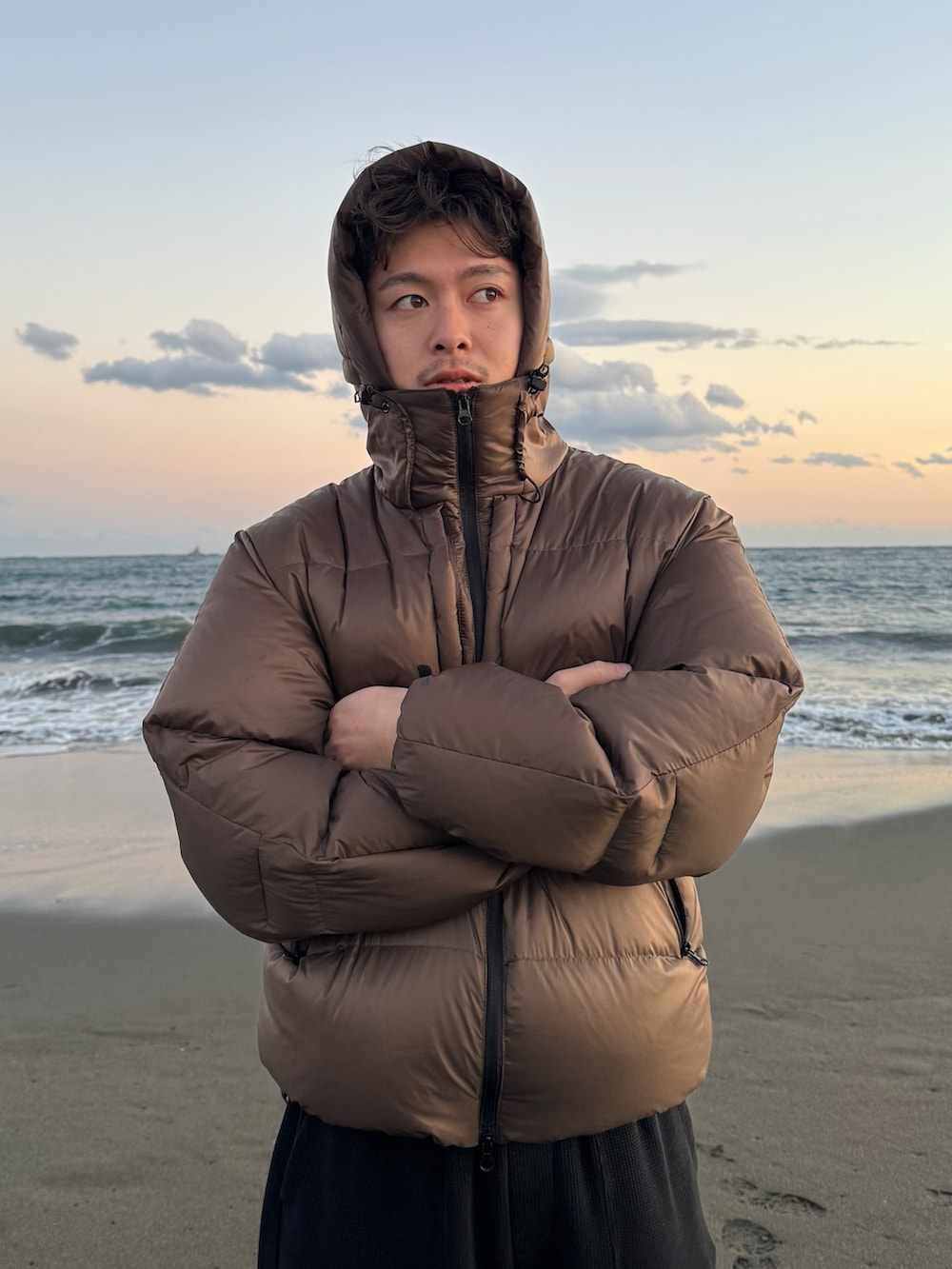 ブラック系のチノパンツ、ブラウン系のダウンジャケット/コート、ブラック系のスニーカーを着用したメンズの冬コーディネートの2枚目の写真