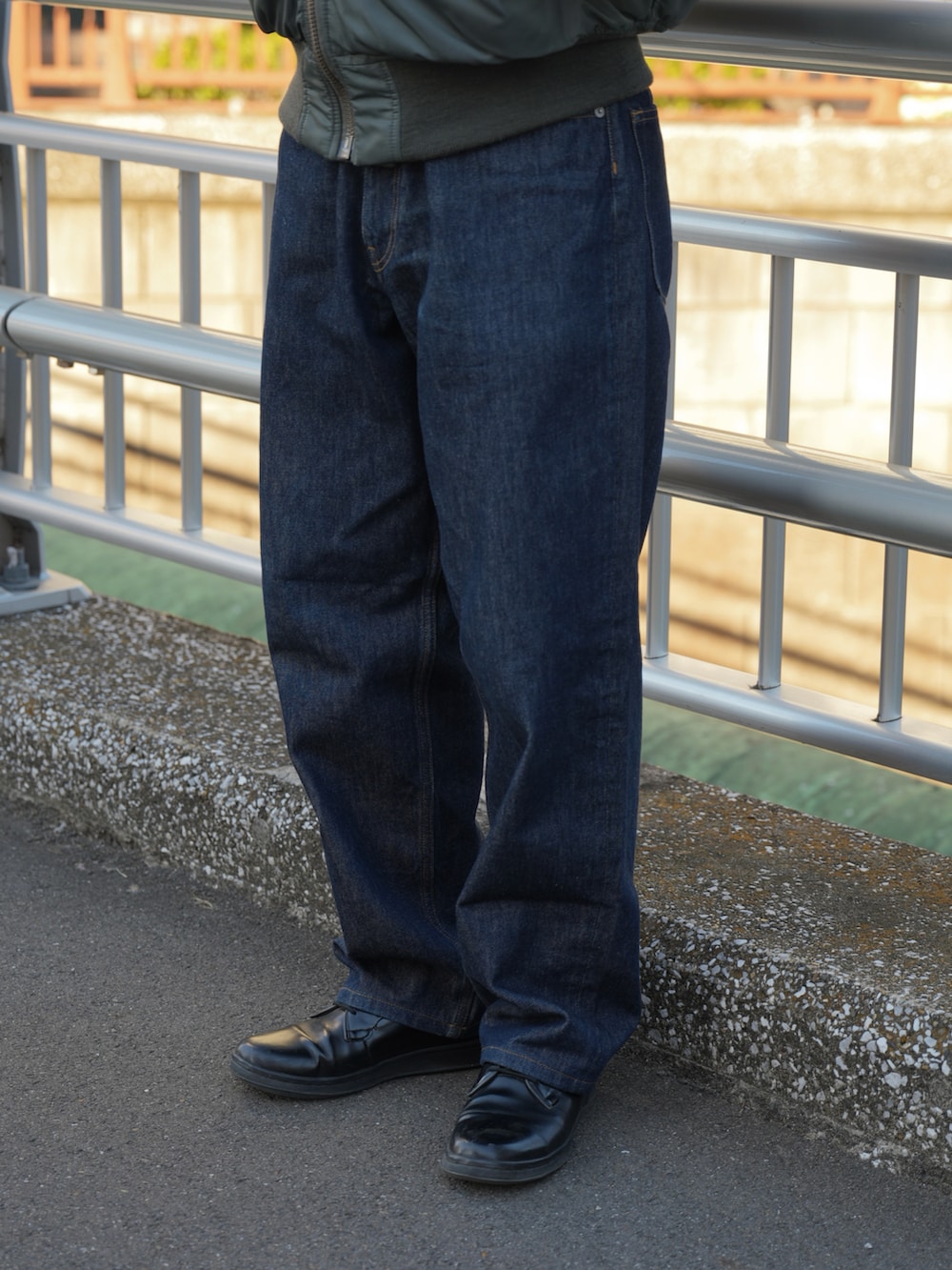 グリーン系のMA-1、ブルー系のデニムパンツ、ブラック系のドレスシューズを着用したメンズの春コーディネートの4枚目の写真