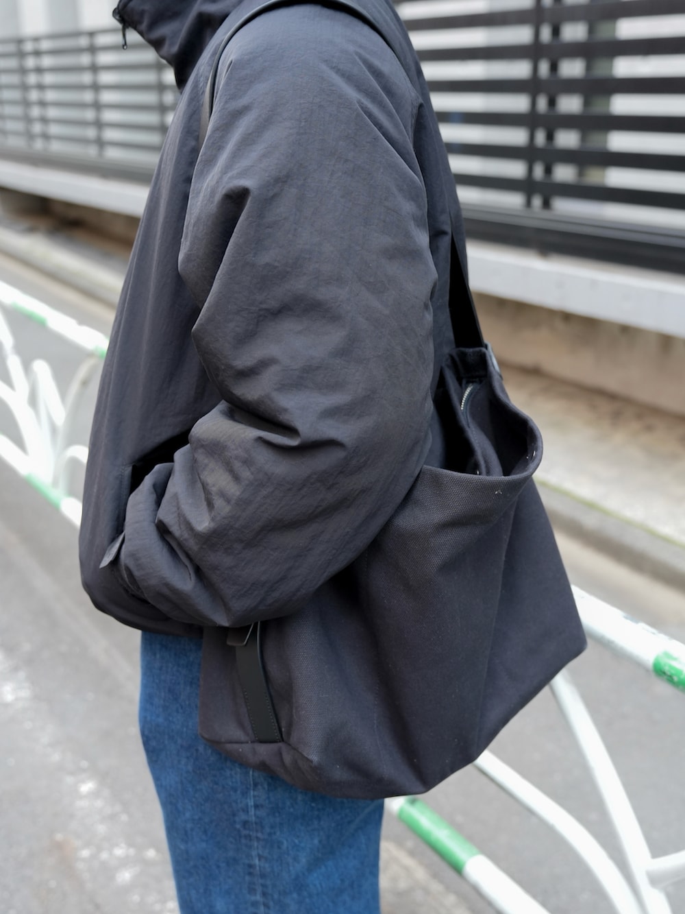 ブルー系のデニムパンツ、ブラック系のドレスシューズ、ブルー系のメッセンジャーバッグを着用したメンズの冬コーディネートの3枚目の写真
