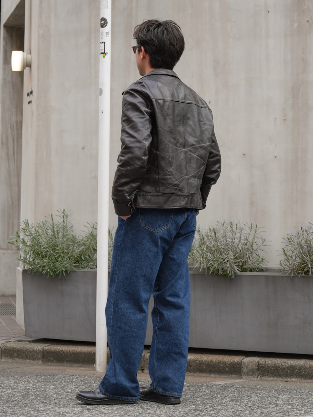 ブルー系のデニムパンツ、ブラック系のジャケット/アウター、ブラウン系のサングラスを着用したメンズの春コーディネートの2枚目の写真