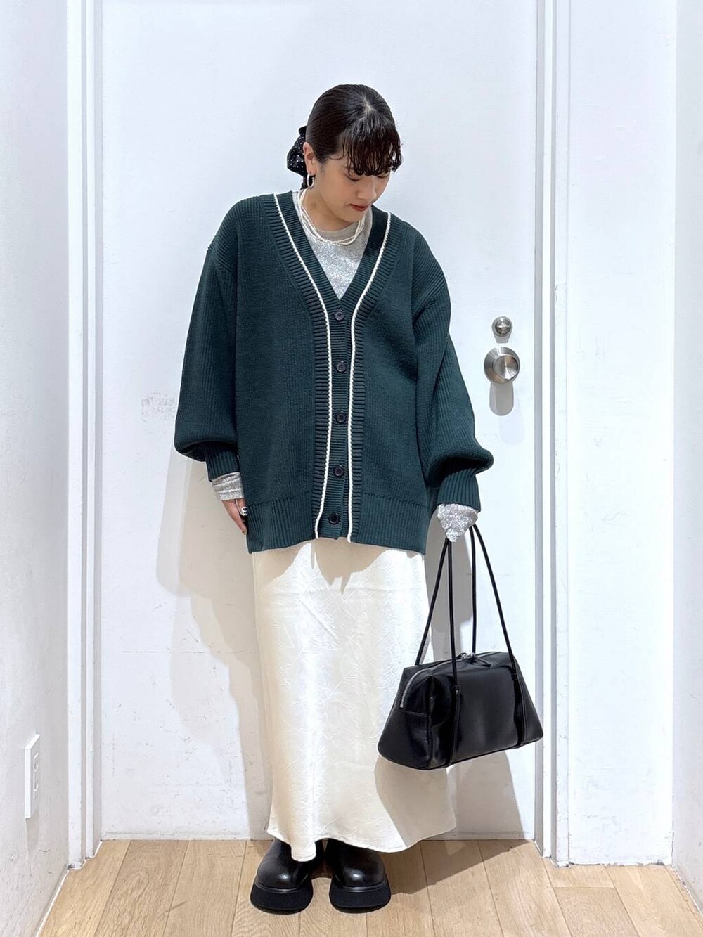 ホワイト系のスカート、グリーン系のカーディガン/ボレロ、ブラック系のボストンバッグを着用したレディースの秋コーディネートの2枚目の写真