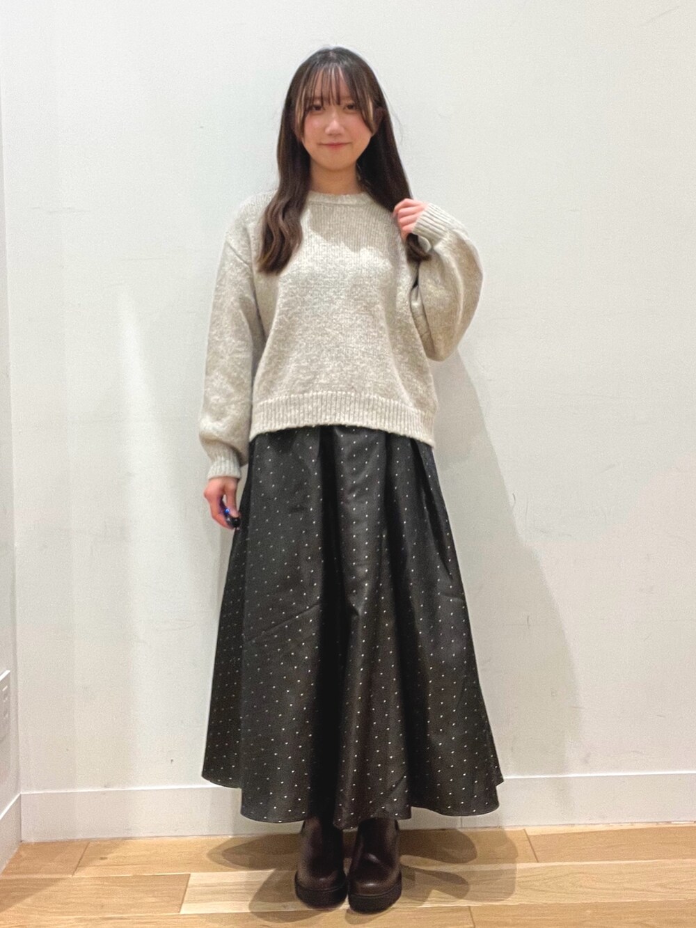 ブラウン系のスカート、グレー系のニット/セーター、ホワイト系のその他アウターを着用したレディースの冬コーディネートの2枚目の写真