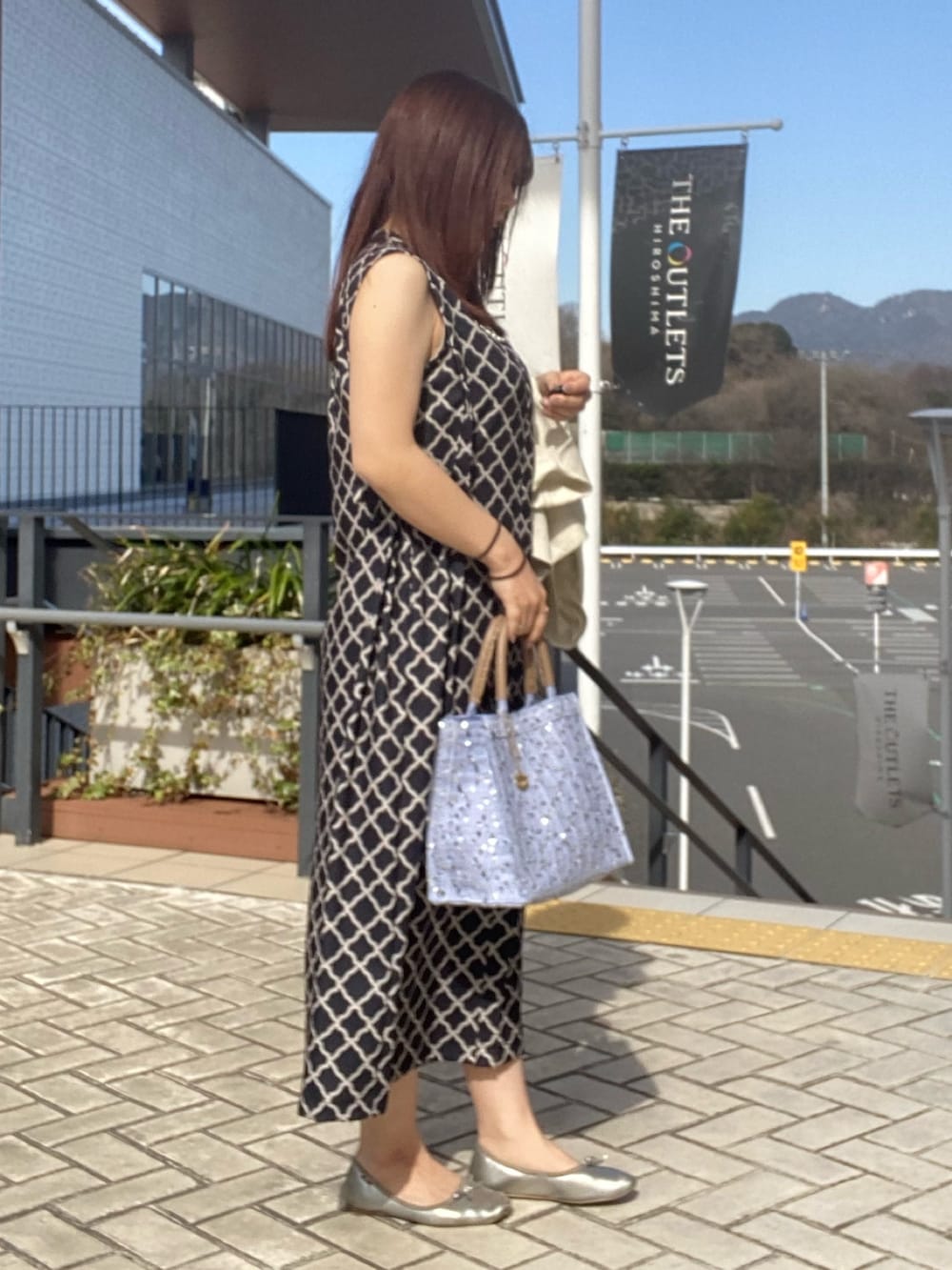 ブラック系のワンピース、ホワイト系のテーラードジャケットを着用したレディースの春コーディネートの2枚目の写真