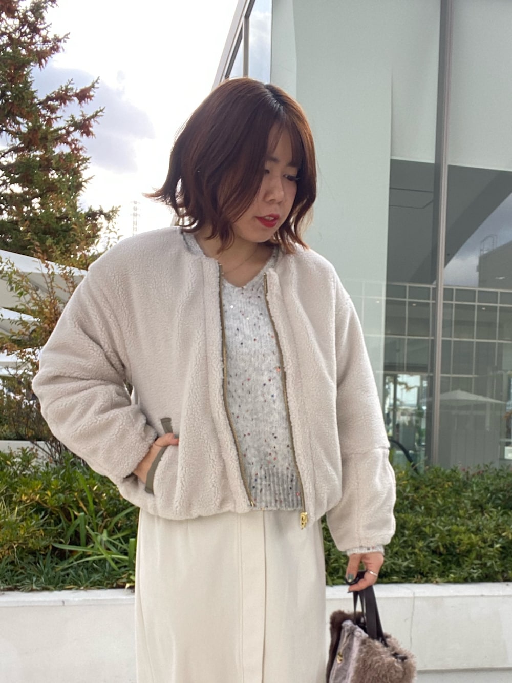 グリーン系のブルゾン、グレー系のニット/セーター、ホワイト系のスカートを着用したレディースの冬コーディネートの4枚目の写真