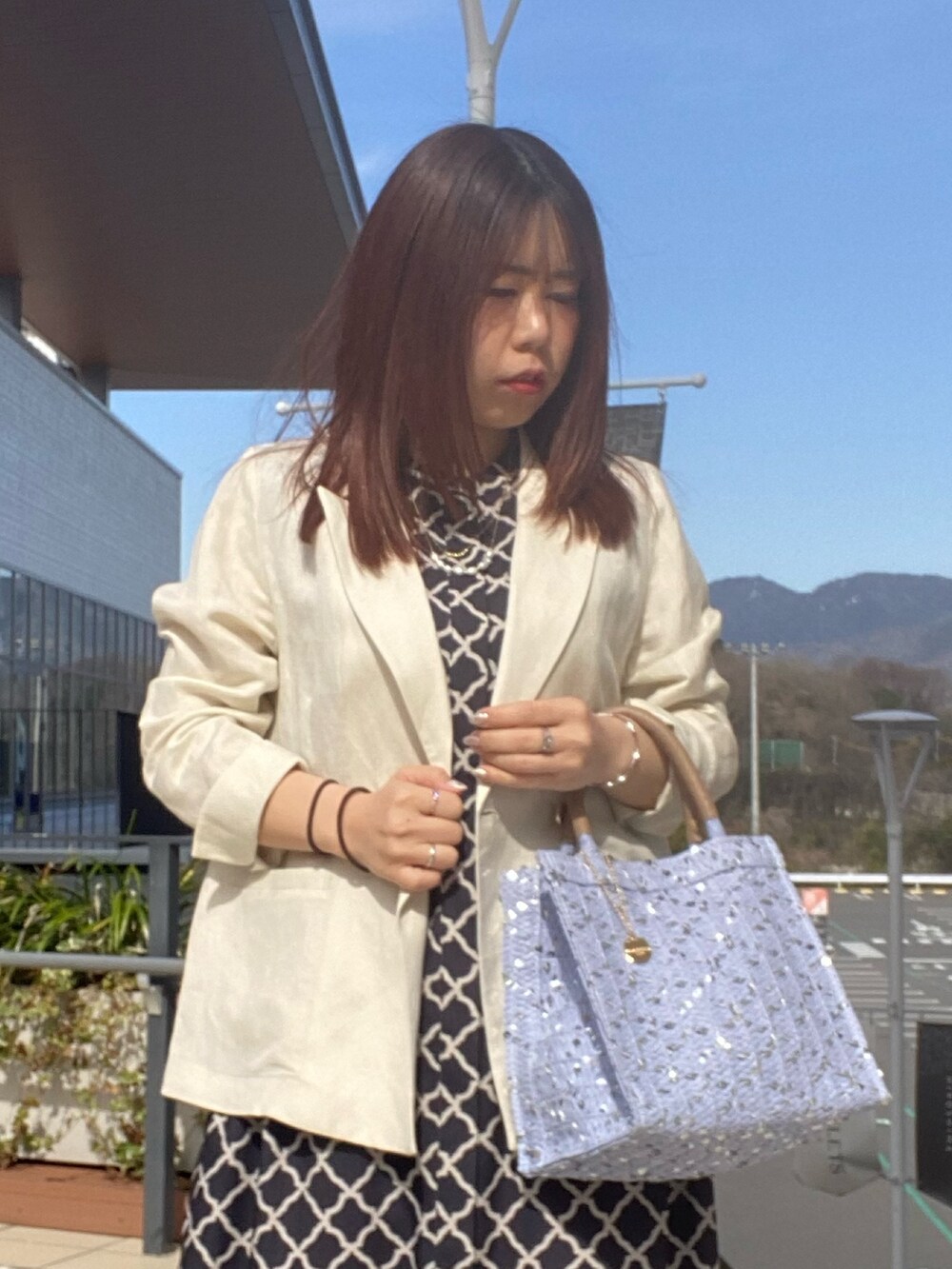 ブラック系のワンピース、ホワイト系のテーラードジャケットを着用したレディースの春コーディネートの4枚目の写真