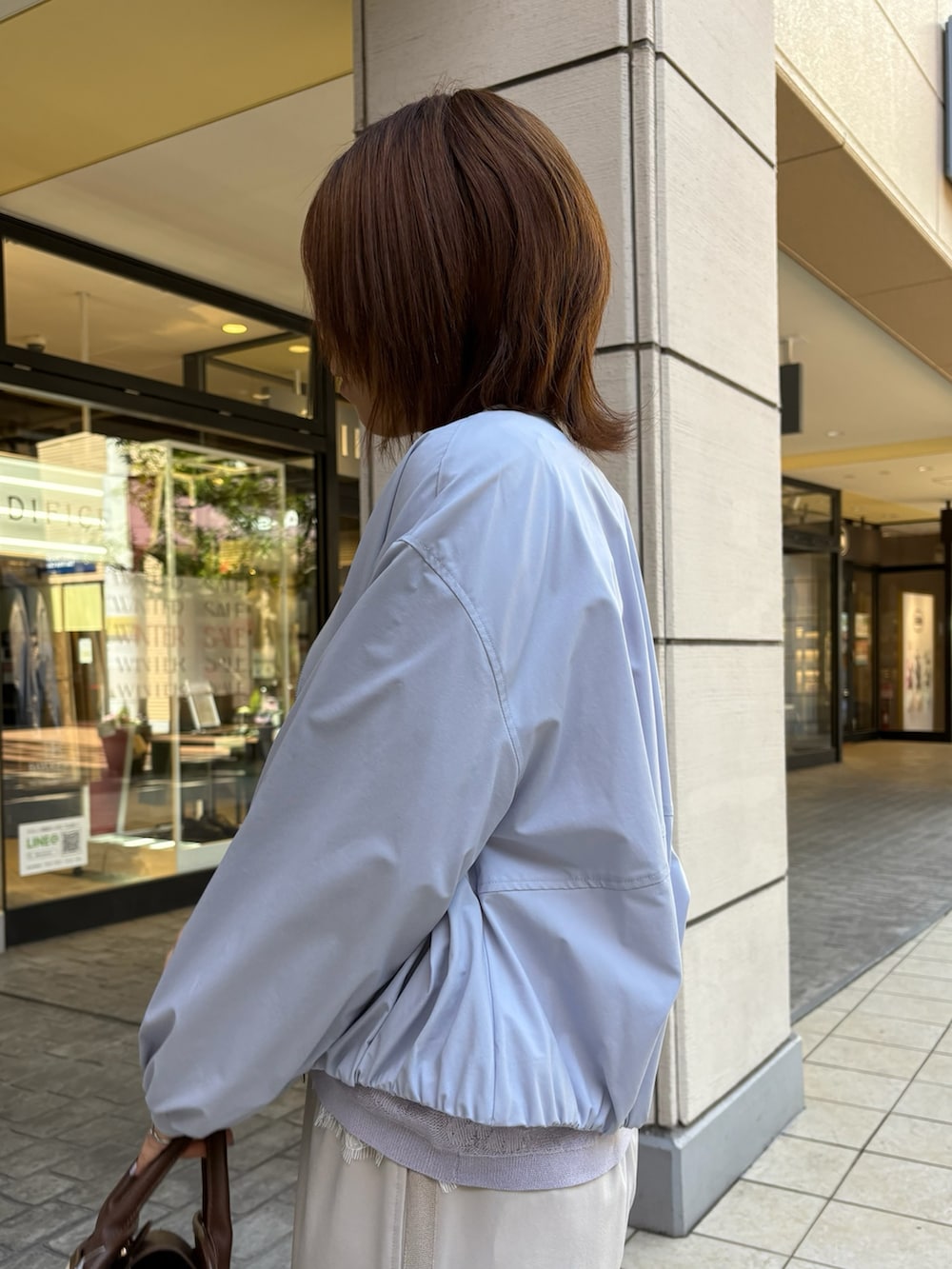 ブルー系のブルゾン、パープル系のニット/セーター、ホワイト系のTシャツ/カットソーを着用したレディースの春コーディネートの5枚目の写真