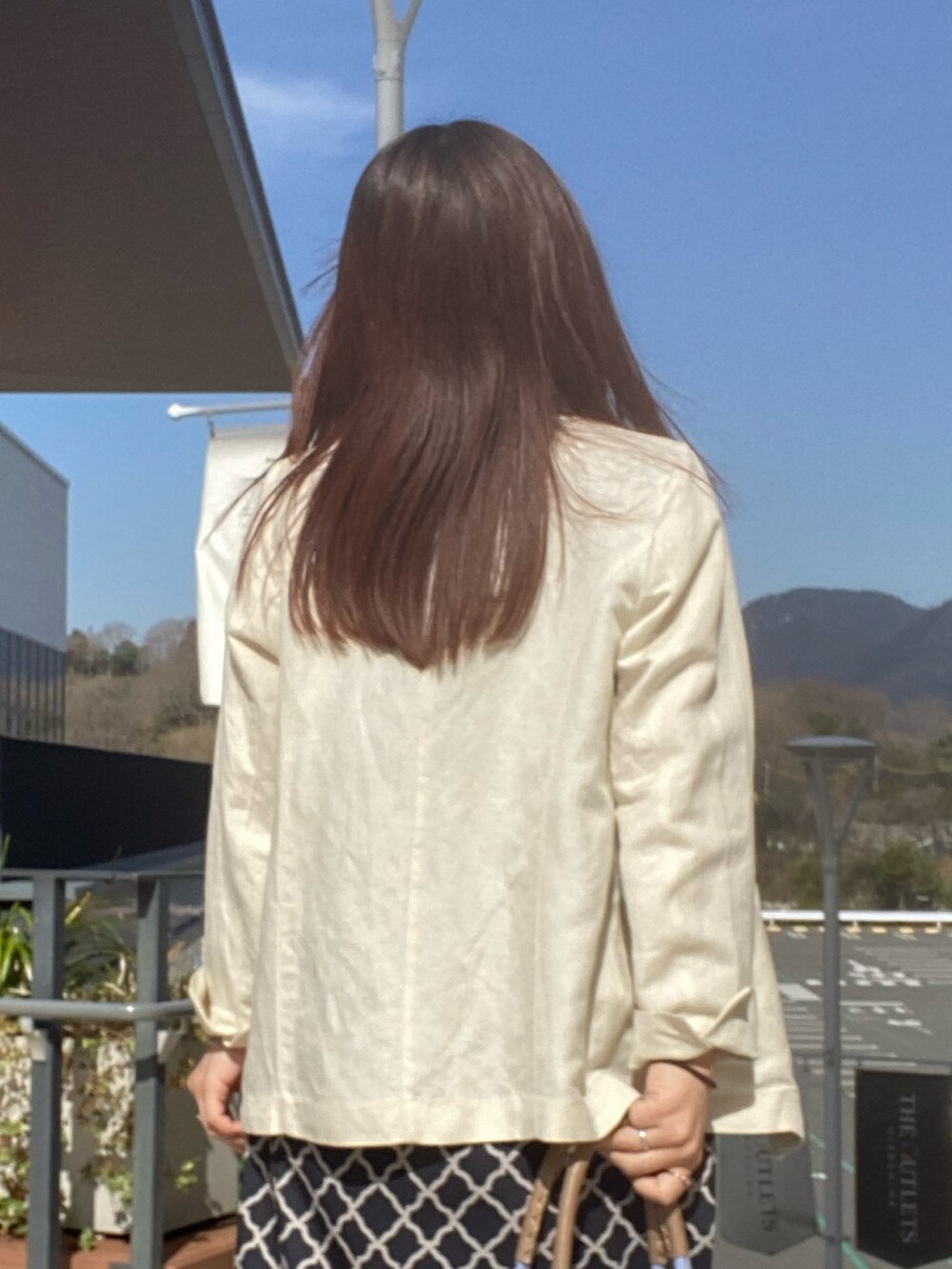 ブラック系のワンピース、ホワイト系のテーラードジャケットを着用したレディースの春コーディネートの6枚目の写真