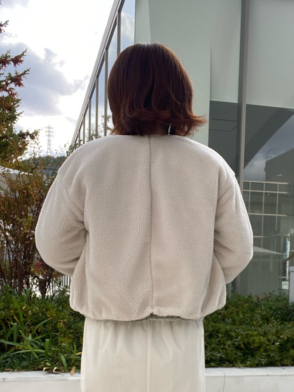 グリーン系のブルゾン、グレー系のニット/セーター、ホワイト系のスカートを着用したレディースの冬コーディネートの6枚目の写真