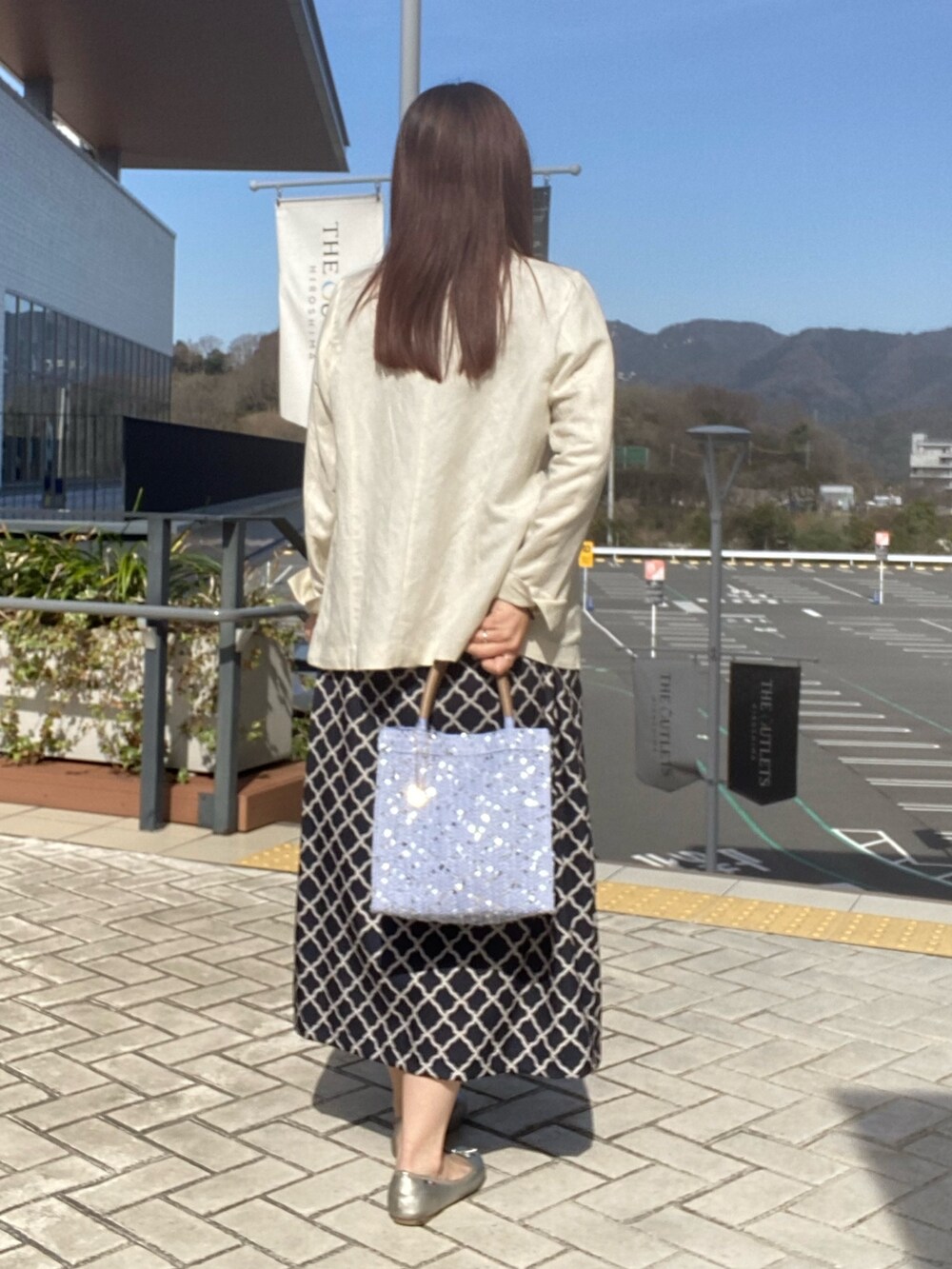 ブラック系のワンピース、ホワイト系のテーラードジャケットを着用したレディースの春コーディネートの3枚目の写真